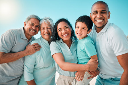 Family, portrait and happy outdoor at beach with a smile, happiness and care together on vacation. Smile of parents, grandparents and boy kid or men and women on holiday with summer sky to relaxの写真素材