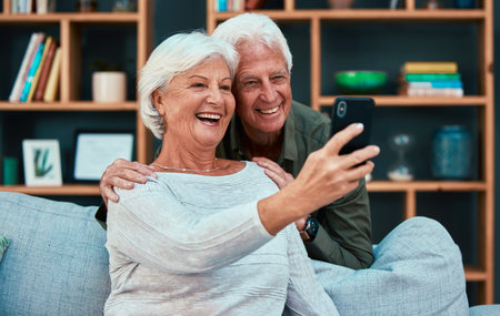 Senior couple, selfie and video call with phone in living room, lounge or family home. Happy,...