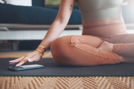 Guided apps make exercising a lot easier. Closeup shot of an unrecognisable woman using a cellphone while exercising at home.の写真素材