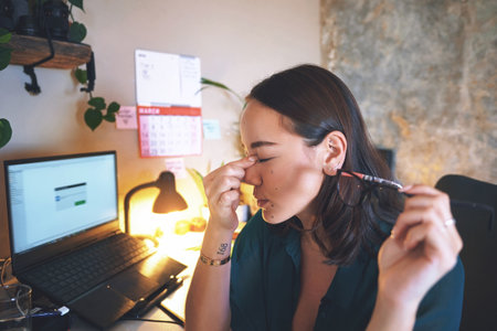 I think a break is in order. an attractive young woman sitting alone and feeling stressed while working from home.の写真素材