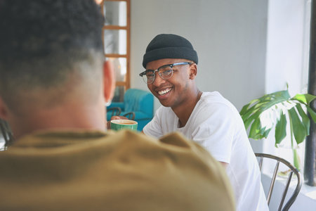 It cant be all work all the time. a handsome young man sitting with a friend in a coffeeshop during the day.の写真素材