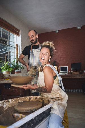 This weekends forecast Arty with sprinklings of fun. a young man and woman working with clay in a...