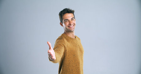 The pleasures all mine. Studio shot of a handsome young man extending his arm for a handshake...