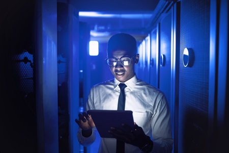 Here to certify the best connection for you. a young man using a digital tablet while working in a server room.の写真素材