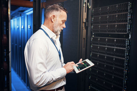 He works faster than your average fibre connection. a mature man using a digital tablet while working in a server room.の写真素材