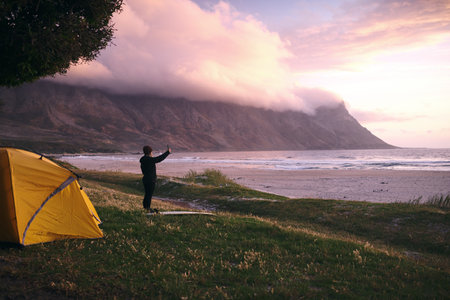 This view is mesmerizing. an attractive young woman camping at her favourite surfing spot.の写真素材