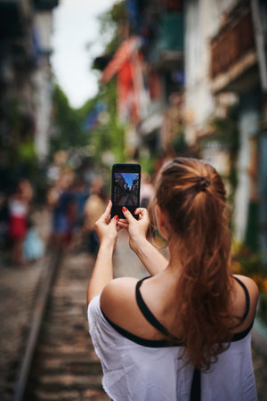 This will be all over the internet. a young woman taking pictures while exploring a foreign city.の写真素材