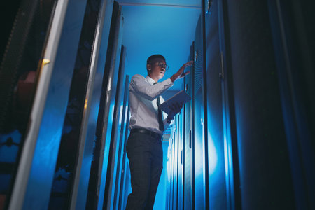 Checking the unit number. a young IT specialist standing alone in the server room and using a digital tablet.の写真素材