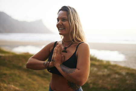 Yoga changes my energy. an attractive young woman standing alone and meditating during a relaxing day outdoors.の写真素材