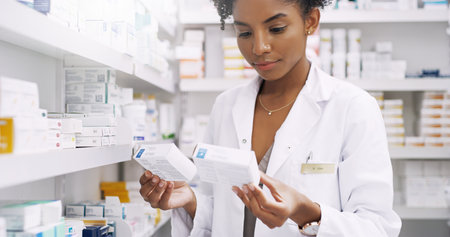 These two are easy to confuse. an attractive young pharmacist comparing two different types of medication in a chemist.の写真素材