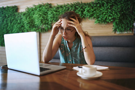 The stressful side of being self employed. a young woman using a laptop and looking stressed while...