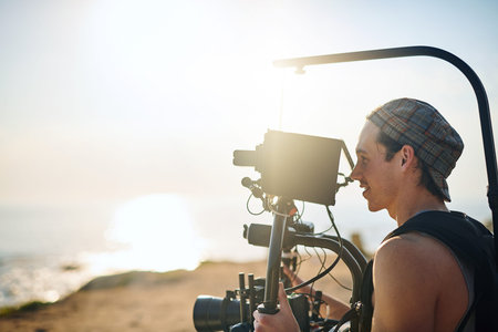 The sun is a bit in the way. a focused young man shooting a scene with a state of the art video...