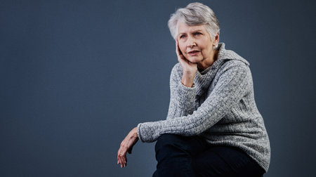 Calm and relaxed. Studio shot a confident elderly woman sitting down and touching the side of her...