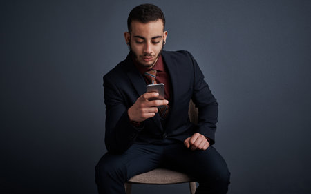 Staying up to date via text. Studio shot of a stylish young businessman sending a text message while...