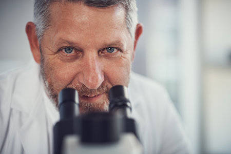 Nothing escapes my eye. Portrait of a mature scientist using a microscope in a laboratory.の写真素材