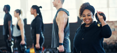 All about that fitness. a cheerful group of young people standing in a row and training with weights...
