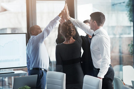 Celebrating another great team endeavor. a group of businesspeople high fiving together while...