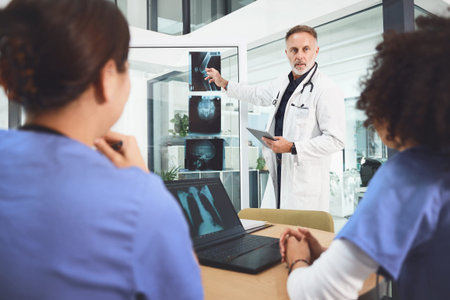 Coming together for another collaborative practice. a mature doctor analysing x-rays with his...