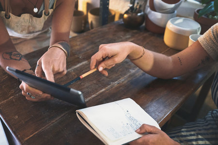 Tapping into their target market. two unrecognisable women using a digital tablet during a meeting...