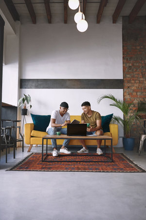 You dont need an office space to run a successful business. two men using a laptop and a digital tablet while having coffee together.の写真素材