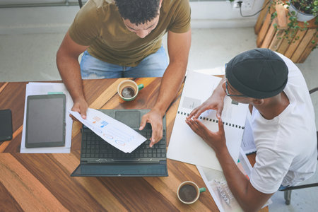 Maybe we could cut back on our expenses. High angle shot of two friends sitting together and using technology during a discussion in a coffeeshop.の写真素材