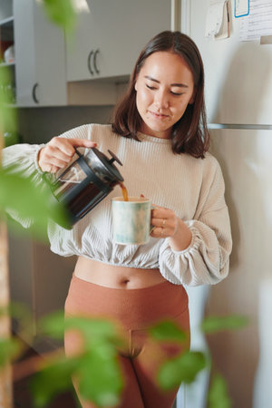 My day doesnt start until the coffee hits. a young woman pouring herself a cup of coffee.の写真素材