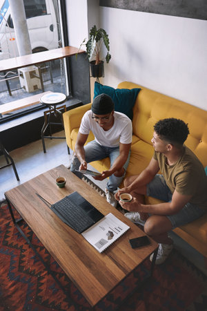 Were so close to getting our business up and running. two men using a laptop and a digital tablet while having coffee together.の写真素材
