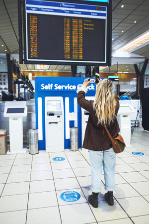 One last pic for the memories. a woman taking a photo of the time for her flight at the airport.の写真素材