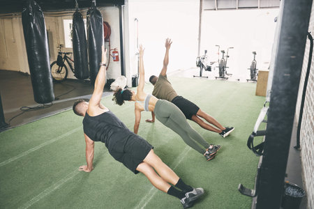Take full advantage of your membership by joining a class. a fitness group doing the side plank together at the gym.の写真素材