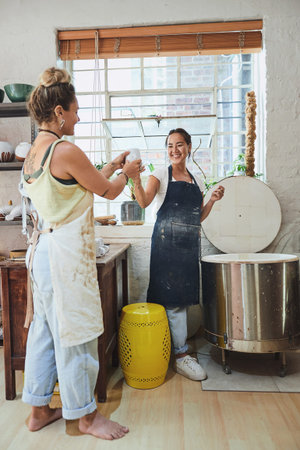 They know quality when they see it. two young women using an electric kiln in a pottery studio.