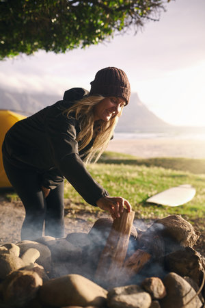 Warming up after a good surfing session. an attractive young woman camping at her favourite surfing spot.の写真素材