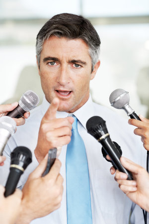Im talking to you. Handsome mature businessman being interviewed by the press.の写真素材