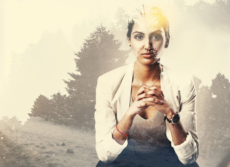 Shes a natural. Portrait of an attractive young businesswoman superimposed over a forest landscape.の写真素材