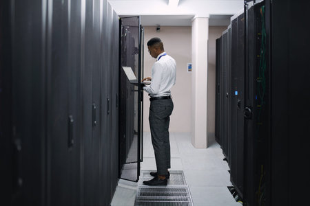 Digital security is of the utmost importance. a young male technician working in a server room.