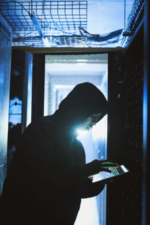 Hacking into your mainframe. a hacker using a digital tablet in a server room.
