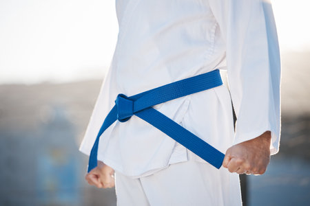 Karate, fitness and discipline with a sports man in gi, training in the city on a blurred background. Exercise, fighter or strong with a male athlete during a self defense workout for health closeupの写真素材