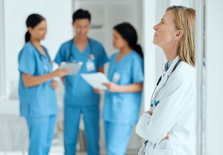 Burnout, anxiety or sad doctor in meeting with nurses with failure, stress or fatigue with medical emergency. Mistake, tired woman or depressed surgeon with depression, trouble or loss in hospitalの写真素材