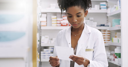 She reads every prescription with care. an attractive young pharmacist looking at a prescription in a chemist.の写真素材