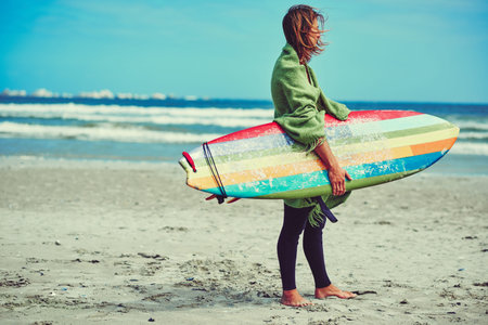 Im here for the waves. a young surfer strolling on the beach with his surfboard.