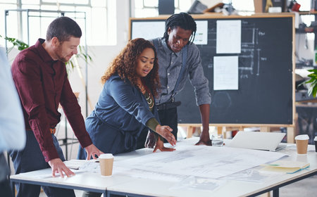 I see the problem here. a team of professionals working on blueprints in an office.の写真素材
