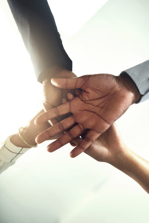 Its all up to us to make this work. Closeup shot of a group of businesspeople joining their hands...