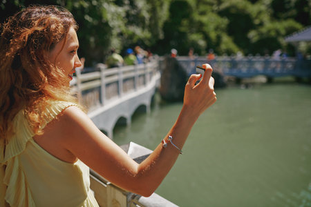 Travel fills your life with beautiful memories. a young woman taking pictures of a river in Vietnam with her smartphone.の写真素材