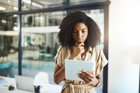 When facing a challenge, she turns to the internet for assistance. a young businesswoman using a digital tablet in an office.の写真素材