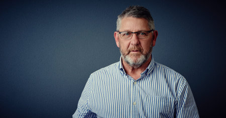 Quietly confident. Studio portrait of a mature businessman posing against a dark background.