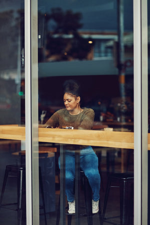Chilling at her favourite cafe. an attractive young woman sitting in a cafe.の写真素材