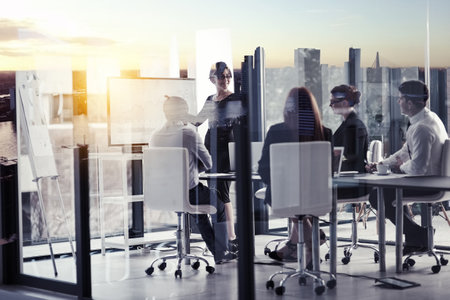 Conquering the city from the boardroom. a corporate business meeting superimposed over a cityscape.の写真素材