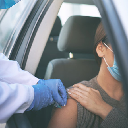 Arm yourself with proection. a masked woman receiving an injection at a Covid-19 drive through testing centre.の写真素材
