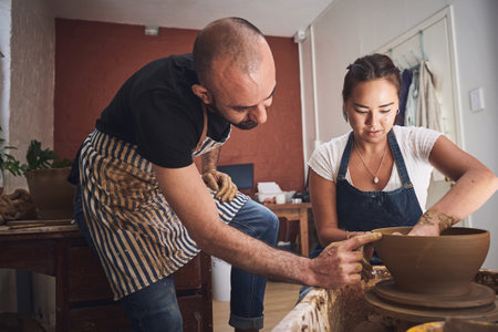 The experience is as important as the finished piece. a young man and woman working with clay in a pottery studio.の写真素材