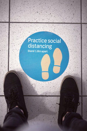 Next in line. a person standing over a sign at the airport.