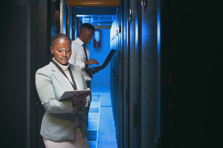 Staying on top of changing data. two young IT specialists standing together in the server room and using technology.の写真素材
